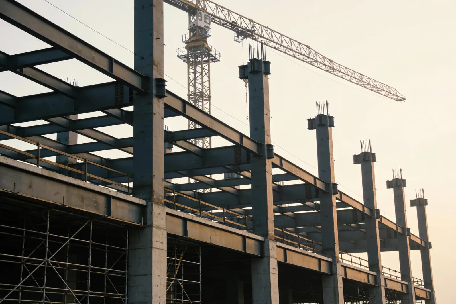 A construction site with a tower crane over a steel frame under erection